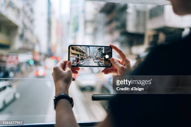 close up of young asian female traveller exploring the city riding local city tram and taking photos of urban city scene with smartphone - spårväg bildbanksfoton och bilder