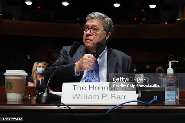 Attorney General William Barr removes his face mask before testifying to the House Judiciary Committee in the Congressional Auditorium at the U.S....