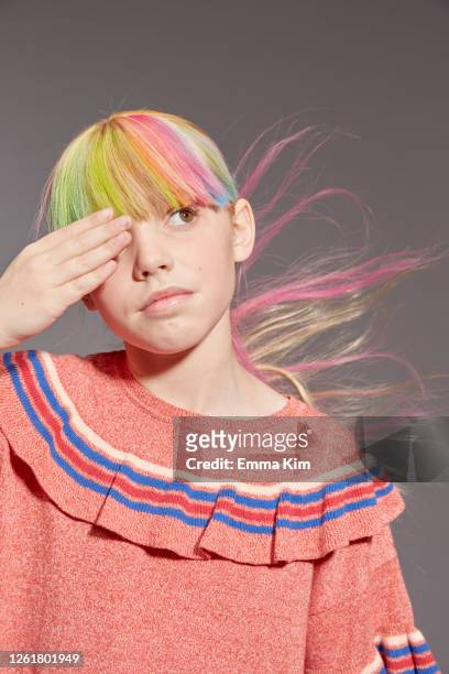 portrait of girl with long blond hair and dyed fringe wearing pink frilly top, looking up, on grey background. - preteen girl models stock pictures, royalty-free photos & images