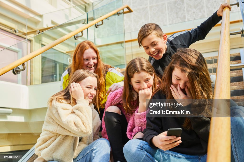 Group of teenage girls in a shopping mall, checking their mobile phones.