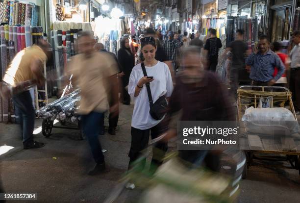 Young Iranian woman without wearing a mandatory headscarf poses for a photograph while using her cell phone in the traditional grand bazaar in...