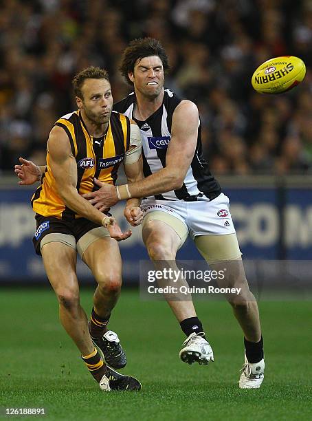 Brad Sewell of the Hawks handballs whilst being tackled by Leigh Brown of the Magpies during the first preliminary final match between the...