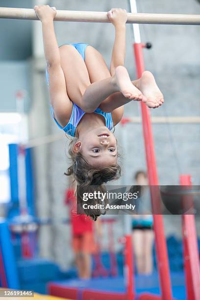 a girl hangs upside down from gymnastics high bar - bar 3 4 stock-fotos und bilder