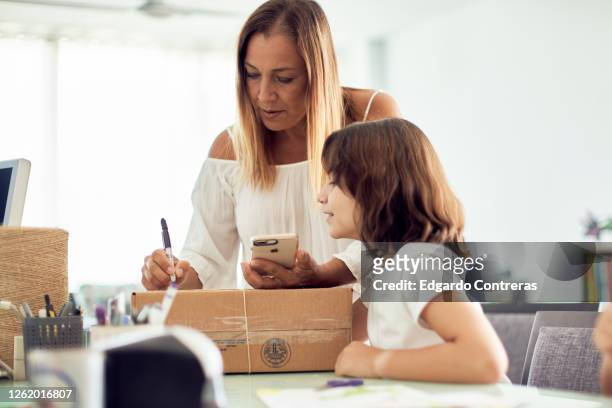 madre e hija empacando un regalo en una caja de cartón - cartón stock-fotos und bilder