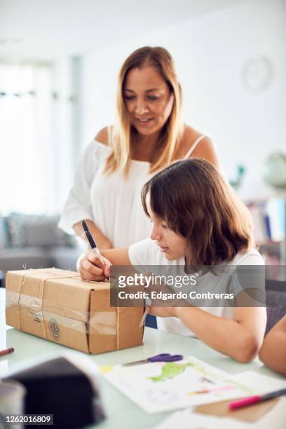 madre e hija empacando un regalo en una caja de cartón - cartón stock pictures, royalty-free photos & images
