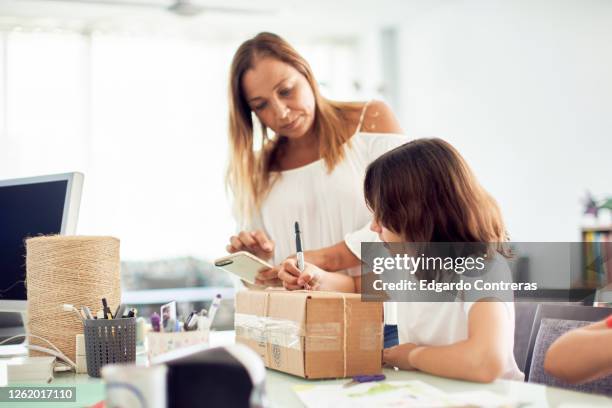 madre e hija empacando un regalo en una caja de cartón - cartón stock-fotos und bilder