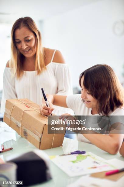 madre e hija empacando un regalo en una caja de cartón - cartón stock pictures, royalty-free photos & images