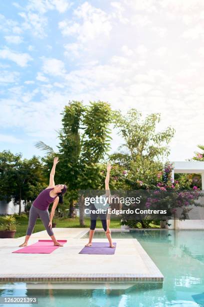 una mujer enseñándole yoga a una niña frente a una piscina - niña isolated stock-fotos und bilder