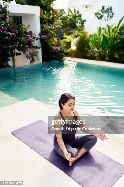 una mujer practicando yoga frente a una piscina - mujer yoga stock pictures, royalty-free photos & images