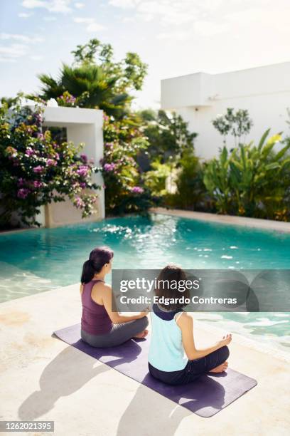 una mujer y una niña de espaldas meditando frente a una piscina - mujer de espaldas foto e immagini stock