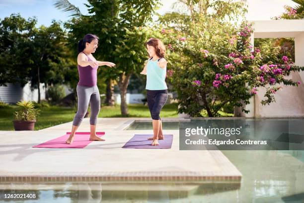 una mujer enseñándole yoga a una niña frente a una piscina - mujer yoga stock pictures, royalty-free photos & images