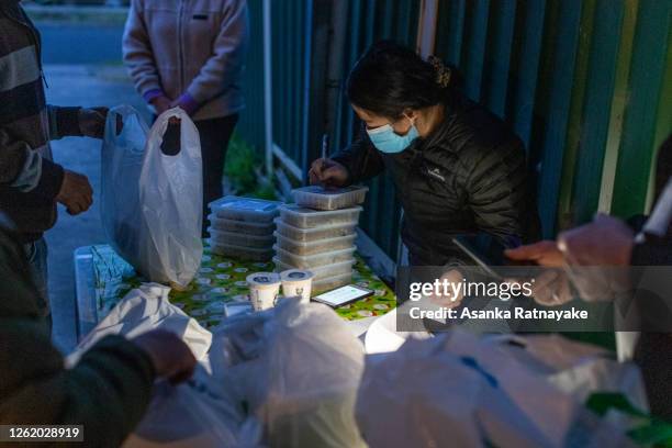 Angelina Sukiri, project Co-ordinator of 'The Kasih Project' is seen marking food package which were prepared by 'Alex Makes food' to members of the...