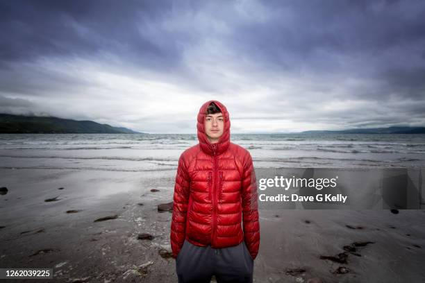 teenage boy standing on a beach at dusk - puffer jacket stock pictures, royalty-free photos & images