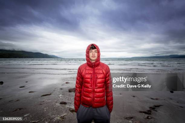 teenage boy standing on a beach at dusk - padded jacket 個照片及圖片檔