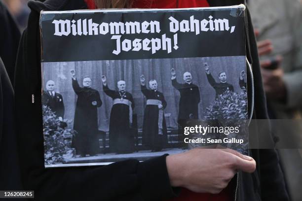 Demonstrator holds a sign that reads: "Welcome home, Joseph" and shows nazi-saluting priests during march against the current visit of Pope Benedict...