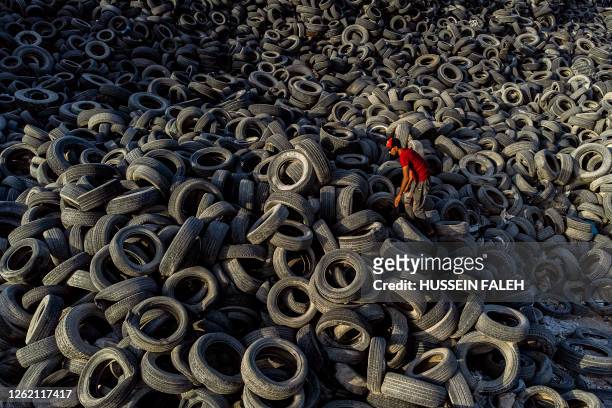 Man stacks damaged tyres in a dump outside Basra in southern Iraq, on June 27, 2023.