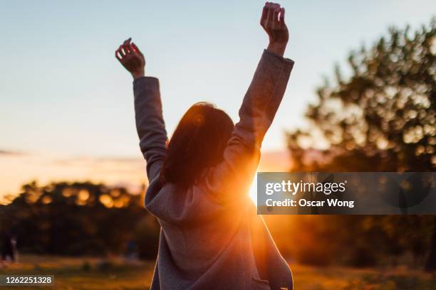 young woman watching sunset while enjoying nature - back stretch stockfoto's en -beelden