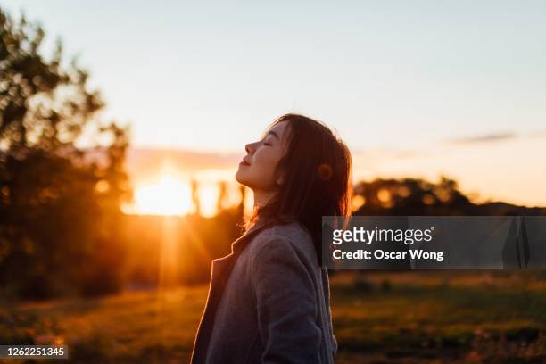 young woman taking a breath of fresh air in nature - tranquilidad fotografías e imágenes de stock
