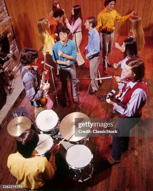 1960s 1970s Group Of Young Boys And Girls Dancing To Music Of Three Piece Rock And Roll Band With Electric Guitars And Drums