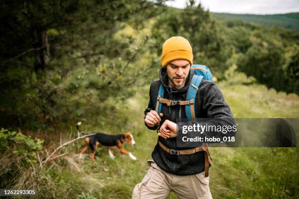 wanderer, der die zeit auf seiner uhr während seines abenteuers überprüft - wandern regen stock-fotos und bilder