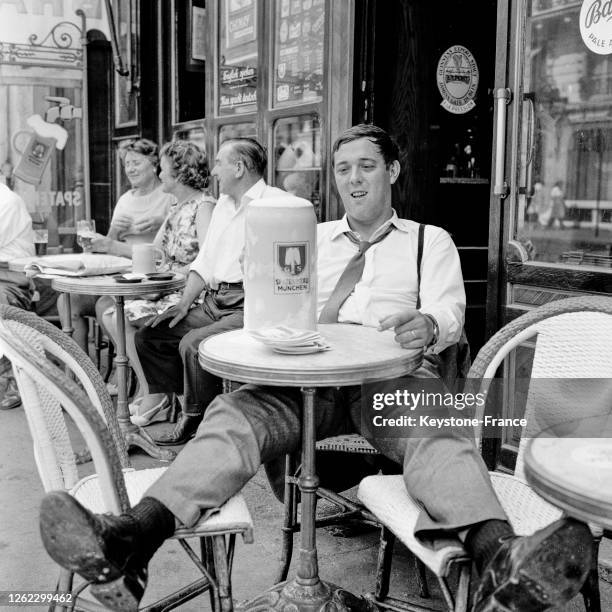 Un Parisien, accablé par la chaleur, a commandé à une terrasse de café une chope géante de bière, à Paris, France le 17 juillet 1964.