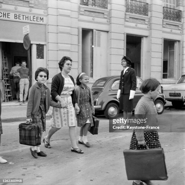 De jeunes écoliers et leur maman traversent dans le passage clouté sous la protection d'une femme-agent, à Paris, France le 18 septembre 1964.