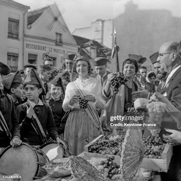 La jeune 'Marianne' de Montmartre admire une grappe de raisin, à Paris, France le 20 septembre 1964.