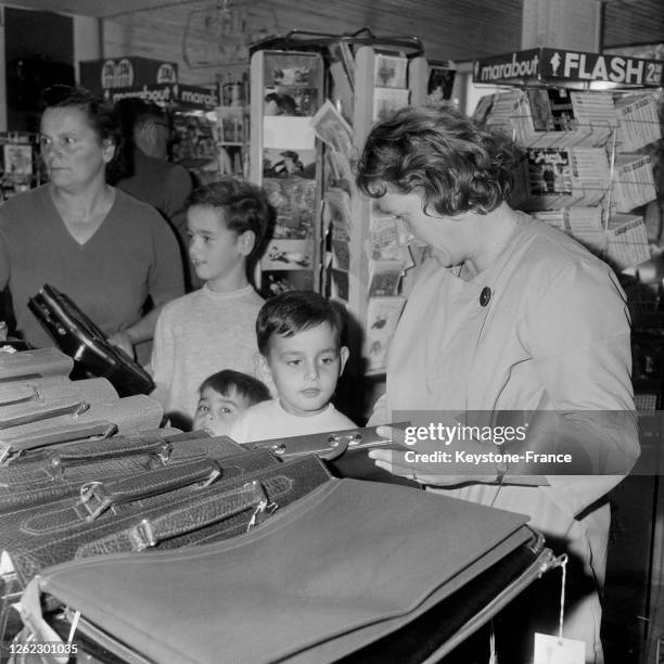 Une maman choisit un cartable pour son enfant, à Paris, France le 8 septembre 1964.