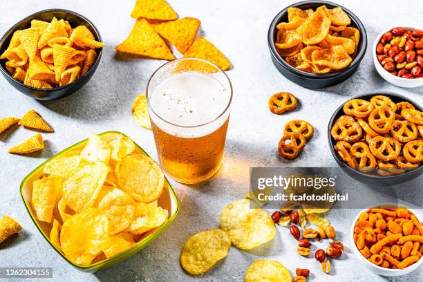 bierglas glas und salzige snacks auf grauen tisch geschossen - beer nuts stock-fotos und bilder