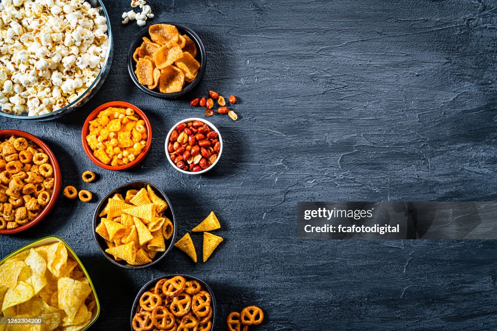 Assortiment de collations salées tirée d’en haut sur la table d’ardoise foncée. Espace de copie