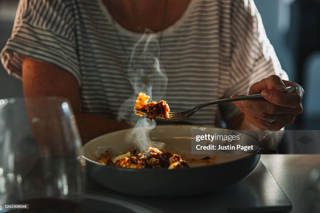 Woman eating fusilli pasta with bolognese sauce