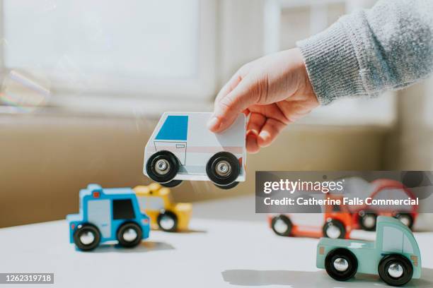 child picking up an ambulance wooden toy - children raising their hands stock pictures, royalty-free photos & images
