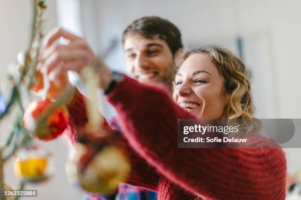 couple decorating christmas tree at home - decorare l'albero di natale foto e immagini stock