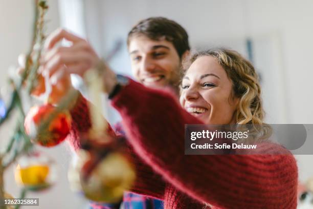 couple decorating christmas tree at home - friends decorating christmas tree stock pictures, royalty-free photos & images