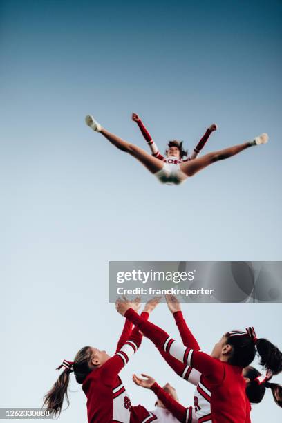 cheerleaders gooien een meisje in de lucht - split acrobatiek stockfoto's en -beelden