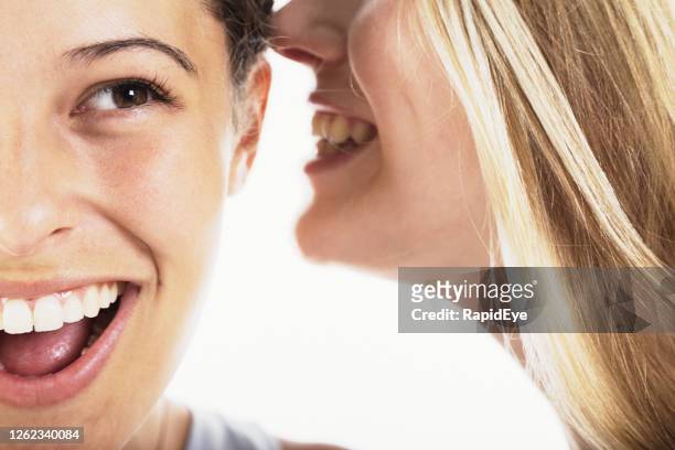 gossiping woman whispers a secret into her girlfriend's ear - girls open mouth imagens e fotografias de stock