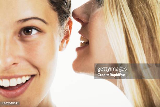 gossiping frau flüstert ihrer freundin ein geheimnis ins ohr - mouth and ear stock-fotos und bilder
