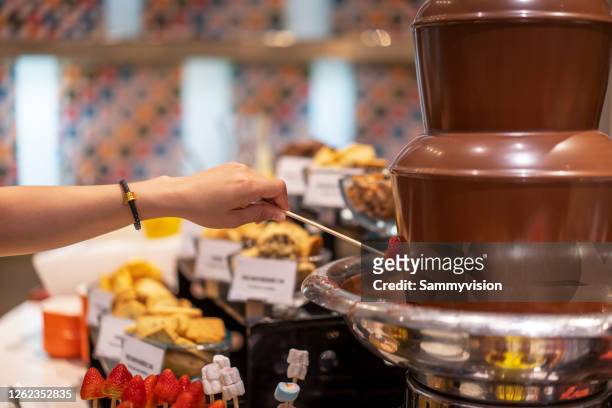 dipping fruit in chocolate fountain - chokladfondue bildbanksfoton och bilder