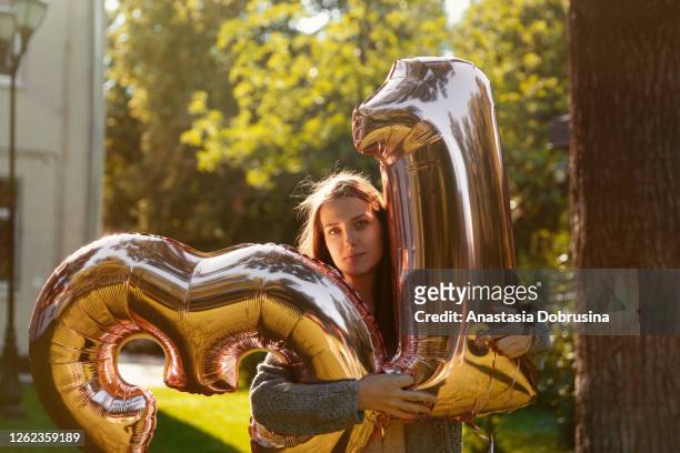 fröhliche frau feiert einunddreißig jahre geburtstag mit großen goldenen luftballons - 30 34 years stock-fotos und bilder