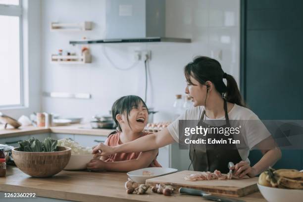 een aziatische chinese moeder die voedsel bij keukenteller met haar dochter voorbereidt - chinese kid stockfoto's en -beelden