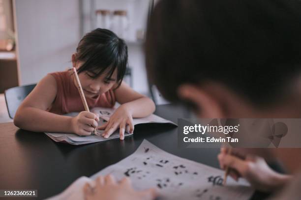2 young children studying at home writing chinese calligraphy in dining room - learning foreign language stock pictures, royalty-free photos & images