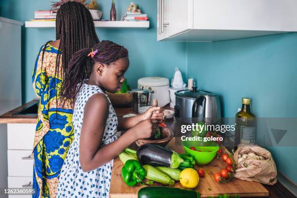 little girl preparing meal with her mother - african mortar and pestle stock pictures, royalty-free photos & images