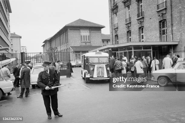 Devant l'hôpital Cochin où a été opéré le général de Gaulle, un agent de police règle la circulation pendant qu'une camionette de police sort de...