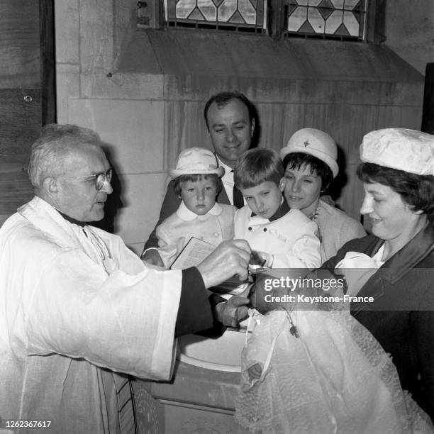 Fernand Raynaud, un peu ému, regarde sa fille Françoise se faire baptiser dans les bras de sa marraine Francine Le Gent, à ses côtés Madame Fernand...