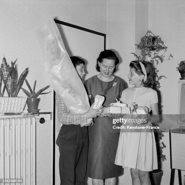 Un garçon et une fille offrent un bouquet de fleurs et des cadeaux à leur maman, en France, le 31 mai 1964.