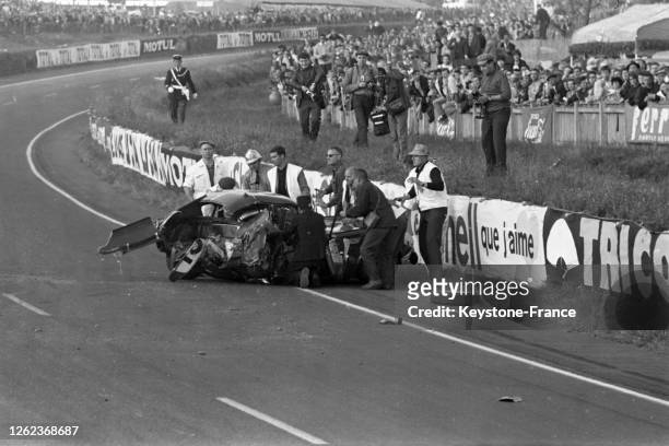 Les sauveteurs se précipitent autour de la 'Triumph' accidentée de Michael Rothschild sur le circuit du Mans, France le 21 juin 1964.