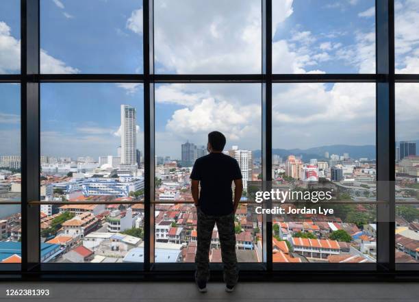 man looking out at george town skyline - georgetown world heritage building stockfoto's en -beelden