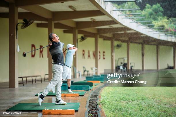 aziatische chinese hogere mensengolfer die weg teeing en zijn golfclub bij golf drijfwaaier slingert - drivingrange stockfoto's en -beelden