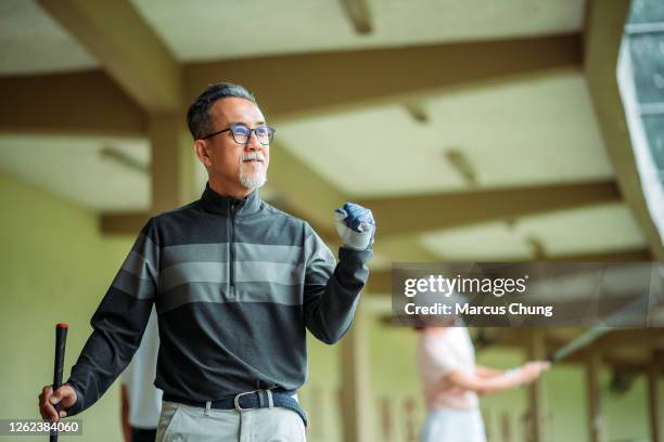 asian chinese senior man golfer saying "yes" at golf driving range - golf excitement stock pictures, royalty-free photos & images