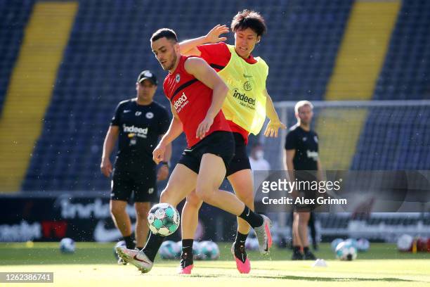 Filip Kostic is challenged by Daichi Kamada during a Eintracht Frankfurt training session at Deutsche Bank Park on July 29, 2020 in Frankfurt am...